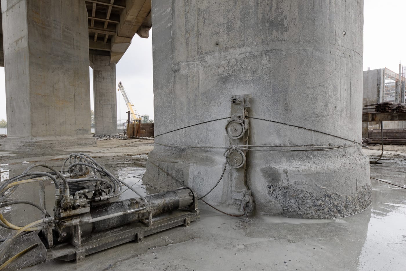 Diamond wire cutting setup around a reinforced concrete pier outdoors